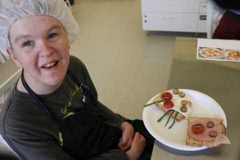 Opiskelija ruokalautasen kanssa pöydän ääressä.